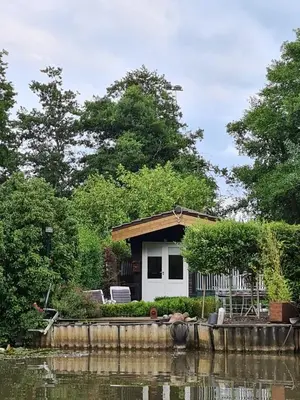 a house on the side of a body of water at Rent & Relax: De steiger in Geel