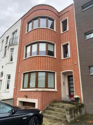 a red brick house with a black car parked in front at Appartements Gustav in Brussels