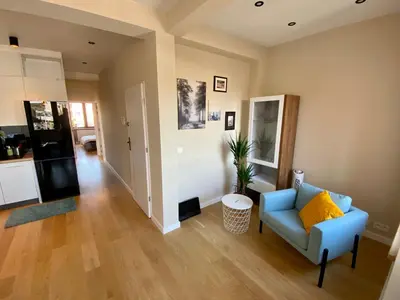 a living room with a blue couch and a kitchen at Appartements Gustav in Brussels