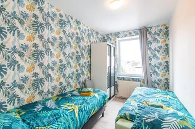 a bedroom with two beds and blue and white wallpaper at VilvoCity Center in Vilvoorde