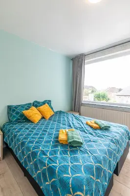 a bedroom with a blue bed with yellow pillows and a window at VilvoCity Center in Vilvoorde