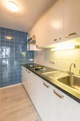 a kitchen with white cabinets and a sink and blue tiles at VilvoCity Center in Vilvoorde