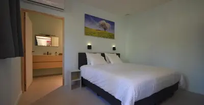 a bedroom with a white bed and a bathroom at B&B Altijd Zomer in Nijlen