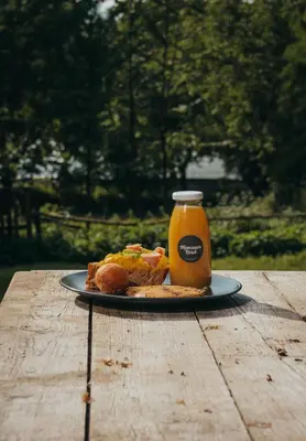 a plate of food and a bottle of orange juice at Tiny House Célestine By Ernesst in Overijse