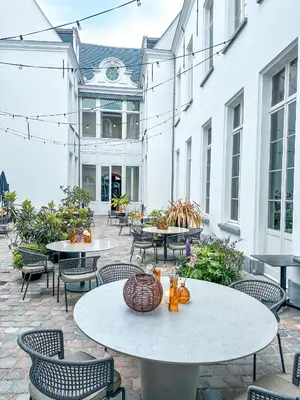 a patio with tables and chairs and a building at Sapphire House Antwerp, Autograph Collection in Antwerp