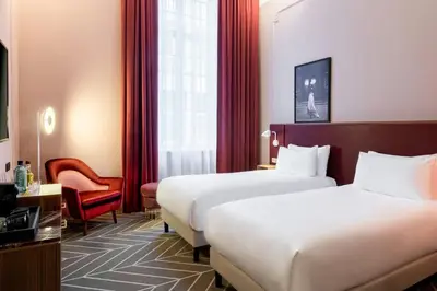 a hotel room with two beds and a chair at Sapphire House Antwerp, Autograph Collection in Antwerp