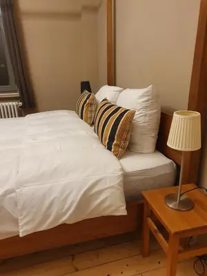 a bed with white sheets and pillows next to a table at Brussels 1904 in Brussels