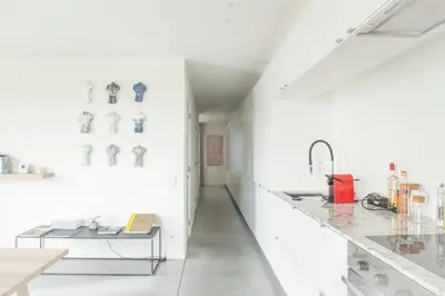 a white kitchen with a counter and a table at Trendy Apartments as Base to Discover Ghent in Ghent