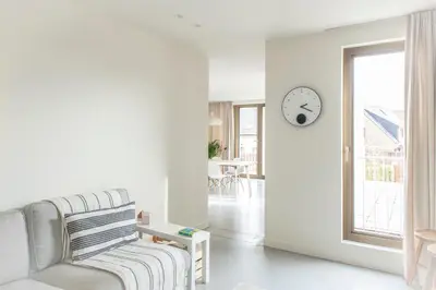 a living room with a couch and a clock on the wall at Trendy Apartments as Base to Discover Ghent in Ghent