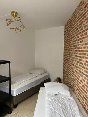 a bedroom with two beds and a brick wall at Apartment de Kerk in Sint-Gillis-Waas