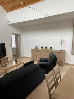 a living room with a black couch and chairs at Apartment de Kerk in Sint-Gillis-Waas