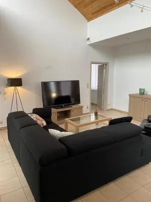 a living room with a black couch and a flat screen tv at Apartment de Kerk in Sint-Gillis-Waas