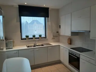 a kitchen with white cabinets and a sink and a window at Apartment de Kerk in Sint-Gillis-Waas