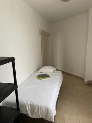a small bedroom with a bed with a green blanket on it at Apartment de Kerk in Sint-Gillis-Waas