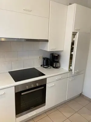 a kitchen with white cabinets and a stove top oven at Apartment de Kerk in Sint-Gillis-Waas