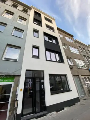 a white building with black windows on a street at Isabel Apartments in Antwerp