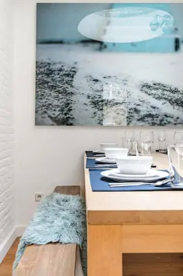 a table with plates and glasses and a painting on the wall at Family Townhouse in the City Centre in Ghent