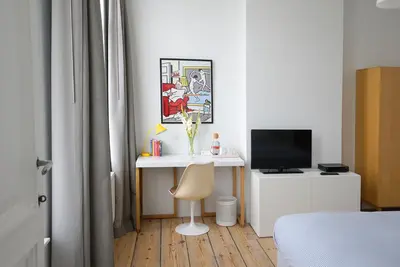 a bedroom with a desk with a computer and a television at B&B Home & the City in Brussels