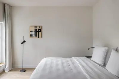 a white bedroom with a bed and a window at Hotel Nenuphar in Ghent