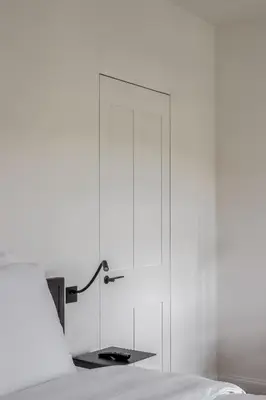 a white bedroom with a bed and a glass door at Hotel Nenuphar in Ghent