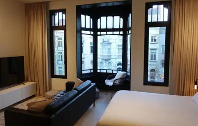 a bedroom with a bed and a couch and windows at Casa Clementina - 3 Bedroom Apartment in a Art-Nouveau House in Ghent