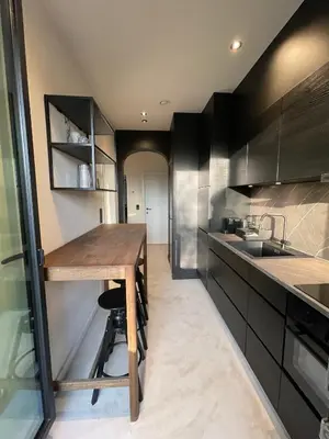 a kitchen with black cabinets and a wooden table at Casa Clementina - 3 Bedroom Apartment in a Art-Nouveau House in Ghent