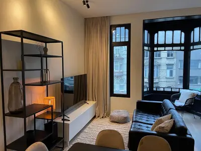 a living room with a couch and some windows at Casa Clementina - 3 Bedroom Apartment in a Art-Nouveau House in Ghent
