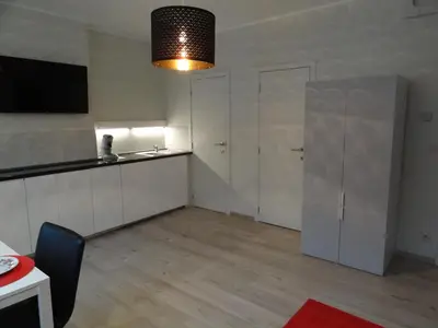 a kitchen with white cabinets and a table and a chair at Albert Studio's in Mechelen