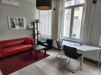 a living room with a red couch and a table at Albert Studio's in Mechelen