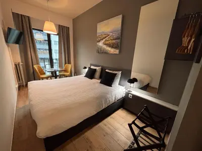 a bedroom with a white bed and a table and chairs at Hotel Aviation in Brussels