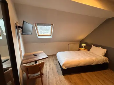 a bedroom with a bed and a table and a window at Hotel Aviation in Brussels