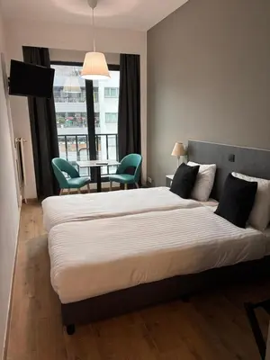 a bedroom with a large bed and a table and chairs at Hotel Aviation in Brussels