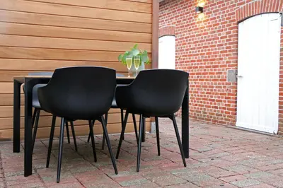 a black table with two black chairs next to a brick wall at Maison des Étoiles in Aalst