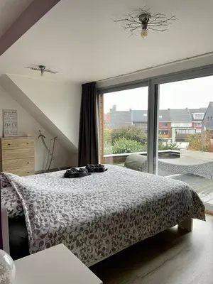 a bedroom with a bed and a large window at Duplex appartement in rustige woonwijk in Mortsel