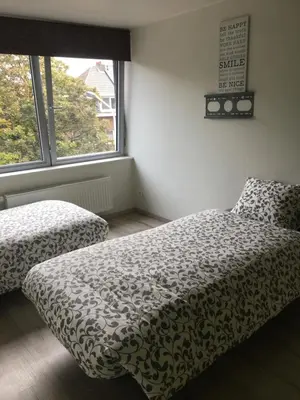 a bedroom with two beds and a window at Duplex appartement in rustige woonwijk in Mortsel