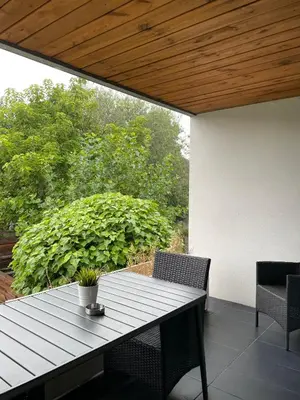 a wooden table and chairs on a patio with a view at Duplex appartement in rustige woonwijk in Mortsel