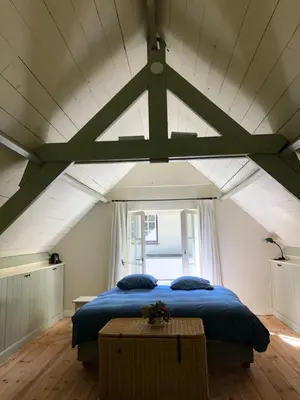 a bedroom with a blue bed and a window at Schilde Cottage in Schilde