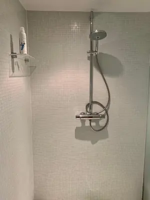 a shower in a bathroom with a tiled wall at Schilde Cottage in Schilde