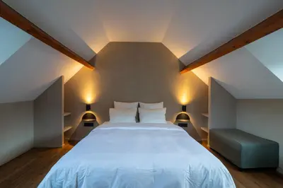 a bedroom with a large white bed and a blue couch at Lovely triplex in the heart of Le Sablon in Brussels