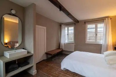 a bedroom with a white bed and a mirror at Lovely triplex in the heart of Le Sablon in Brussels