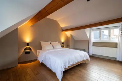 a bedroom with a white bed and a window at Lovely triplex in the heart of Le Sablon in Brussels