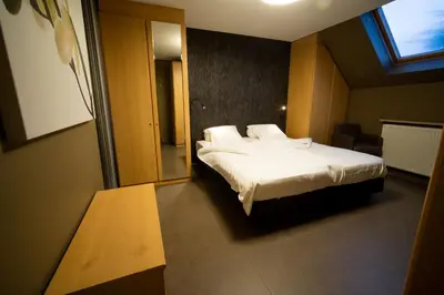 a bedroom with a bed with white sheets and a window at Su'ro Bed and Breakfast in Ghent