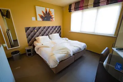 a bedroom with a large bed with white sheets and pillows at Su'ro Bed and Breakfast in Ghent