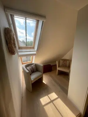 an attic room with a chair and a window at Bouwelhoeve 't Schuur in Grobbendonk