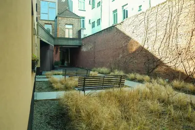 a row of benches sitting next to a brick wall at City Garden Ghent in Ghent