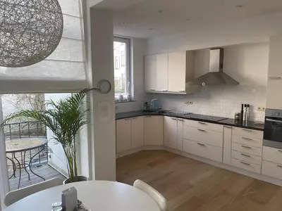 a kitchen with white cabinets and a table and a window at Apartment in trendy Chatelain center Brussels area Little Garden Internet wifi in Brussels