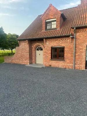 a brick house with a white door and a driveway at De Reynaarthoeve in Assenede