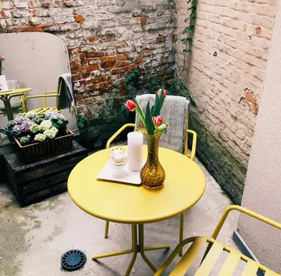 a yellow table with a vase with flowers on it at Studio Dageraad in Antwerp