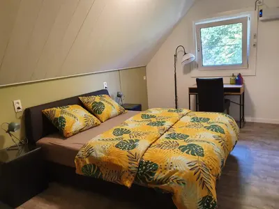 a bedroom with a bed and a desk and a window at De Gorzen in Oud-Turnhout