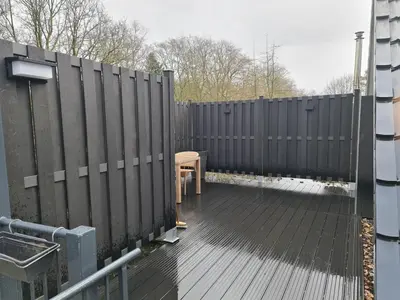 a wooden deck with a fence and a table at De Gorzen in Oud-Turnhout